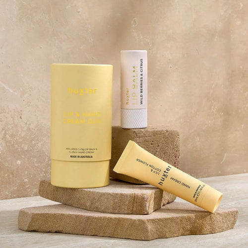 Three skincare products on stone blocks with a beige background