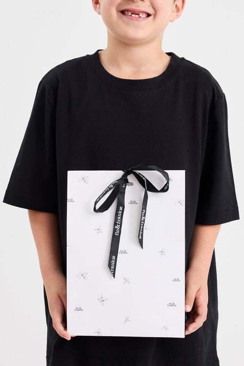 Child holding a wrapped gift with a black ribbon against a white background
