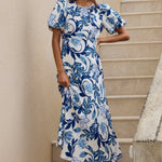 Woman in a blue floral dress standing on stone steps outdoors