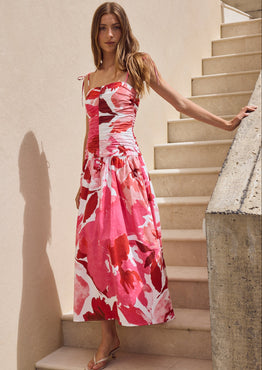 Woman in a red and white floral dress standing on a staircase.