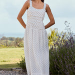 Woman in a white dress standing outdoors with lavender and greenery in the background