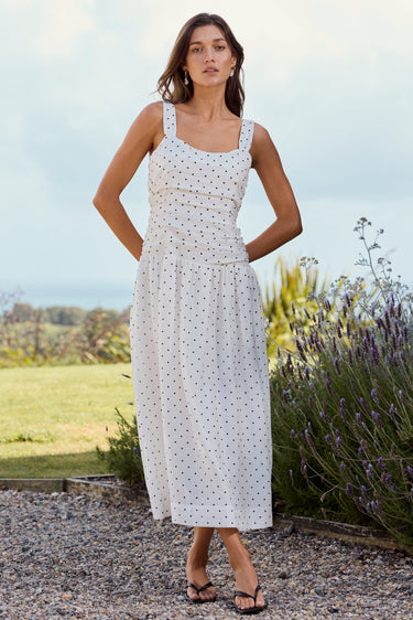 Woman in a white dress standing outdoors with lavender and greenery in the background