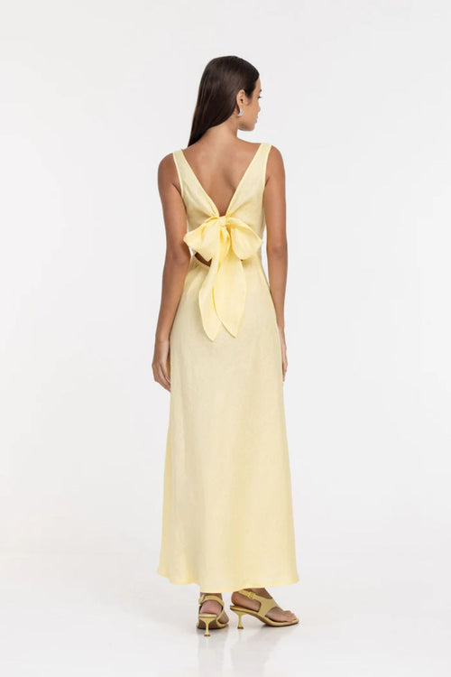 Woman wearing a yellow dress with a bow detail on a white background