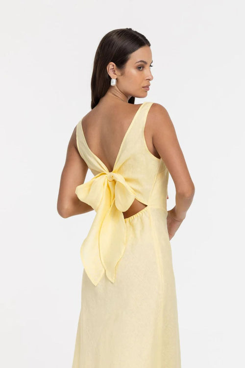 Woman wearing a yellow dress with a bow detail on a white background