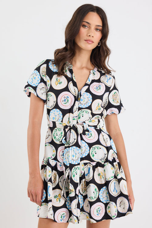 Woman wearing a black dress with colorful floral pattern on a white background