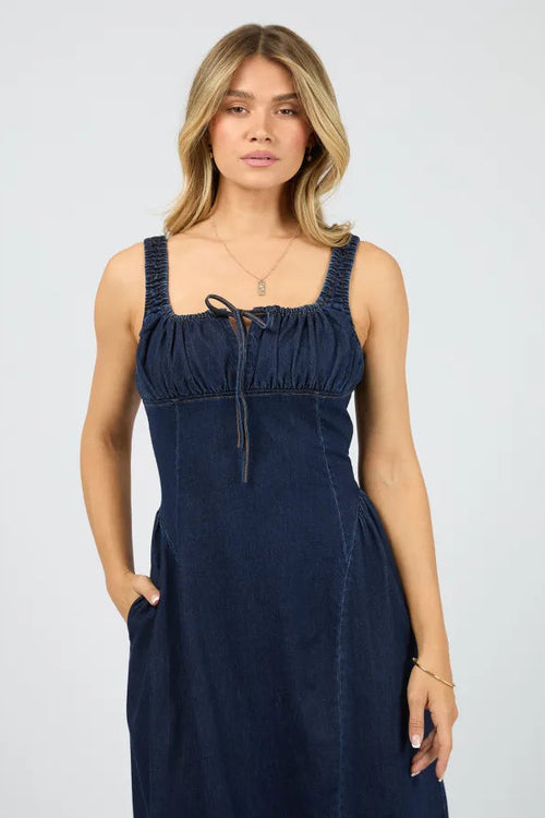 Woman wearing a navy blue dress against a plain background