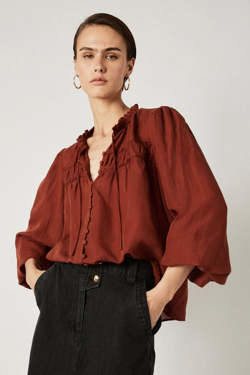 model wears a brown blouse