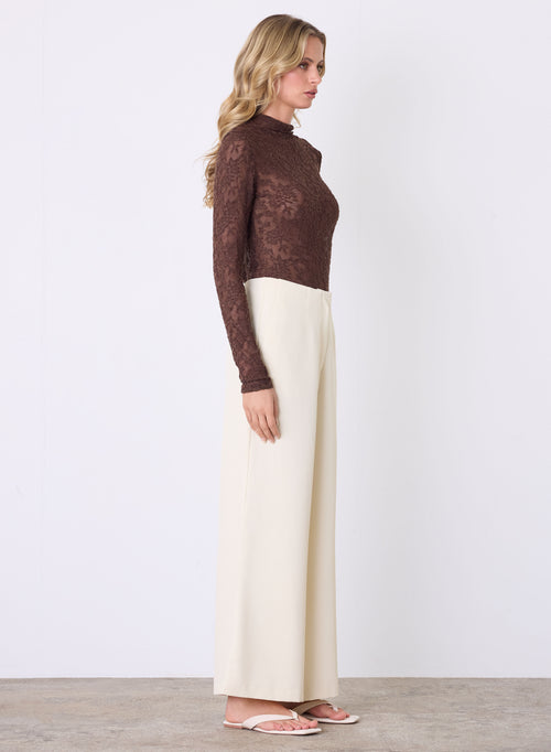 Model wears a lace brown long sleeve top with a high neck