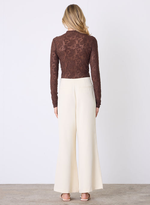 Model wears a lace brown long sleeve top with a high neck