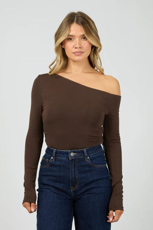 Woman wearing a brown off-shoulder top and blue jeans on a white background
