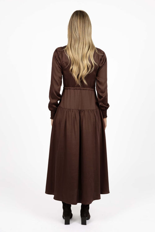 Woman wearing a brown dress with long sleeves on a white background