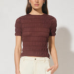 Woman wearing a brown ribbed sweater and beige pants on a white background