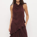 A woman modeling a sleeveless, dark burgundy draped top and matching wide-leg pants set, paired with black flip-flops, against a plain white studio background.
