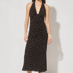 Woman wearing a black dress with white polka dots on a white background