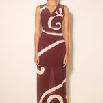 Woman wearing a burgundy dress with white abstract patterns on a beige background