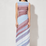 Woman wearing a sleeveless, long, multicolored dress against a white background