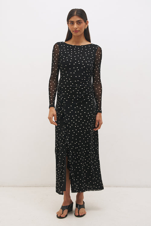 Woman wearing a black dress with white polka dots on a white background