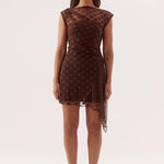 A woman modeling a brown sheer mesh mini dress with a dark brown polka dot pattern, photographed against a seamless white studio background.