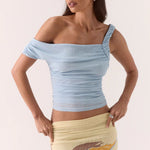 Woman wearing a light blue off-shoulder top and a beige skirt with a pattern.