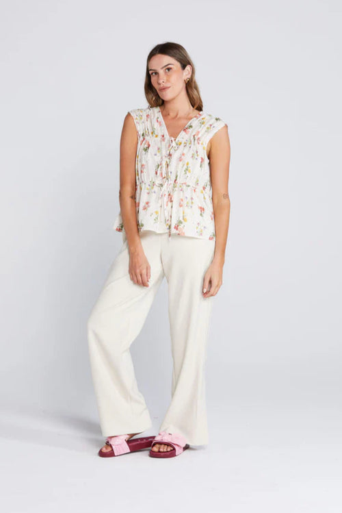 woman wearing a cream floral top and cream pants