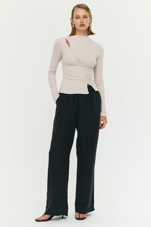 Woman wearing a beige top and black pants on a white background