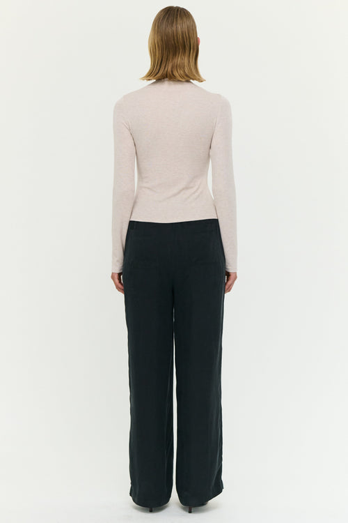 Person wearing a light-colored long-sleeve top and dark pants on a white background