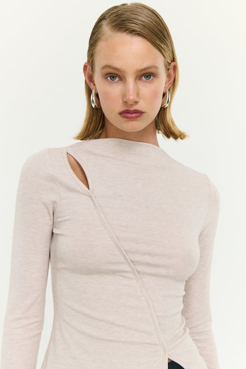 Woman wearing a beige long-sleeve top with a cutout design on a white background
