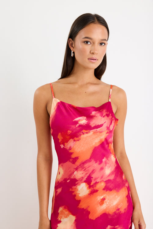 Woman wearing a pink and orange tie-dye dress against a white background