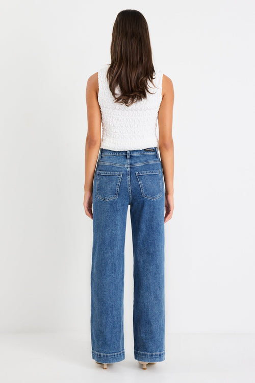 Woman wearing blue jeans and a white top on a white background
