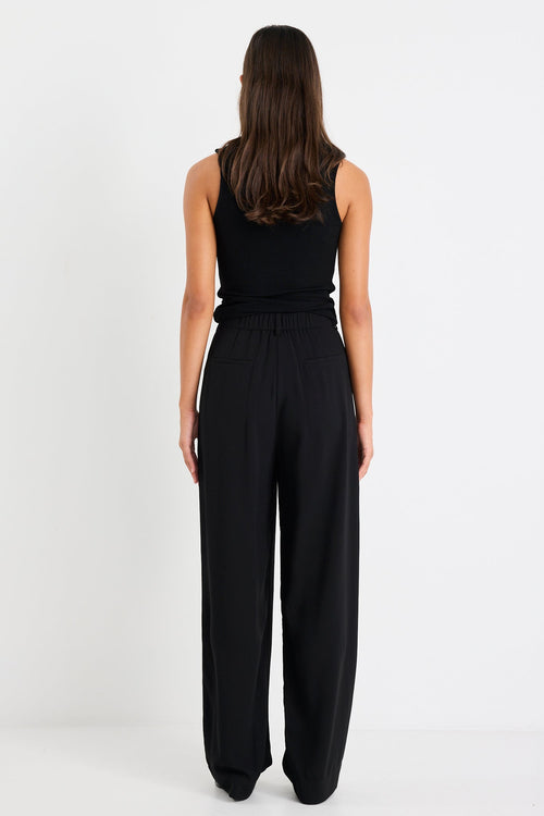 Woman wearing a black sleeveless jumpsuit on a white background