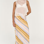 Woman wearing a light pink sleeveless top and striped skirt on a white background