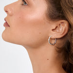 Close-up of a woman wearing a silver hoop earring against a neutral background