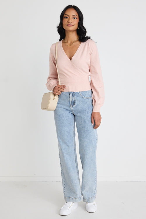 Model wears a pink wrap top with blue jeans