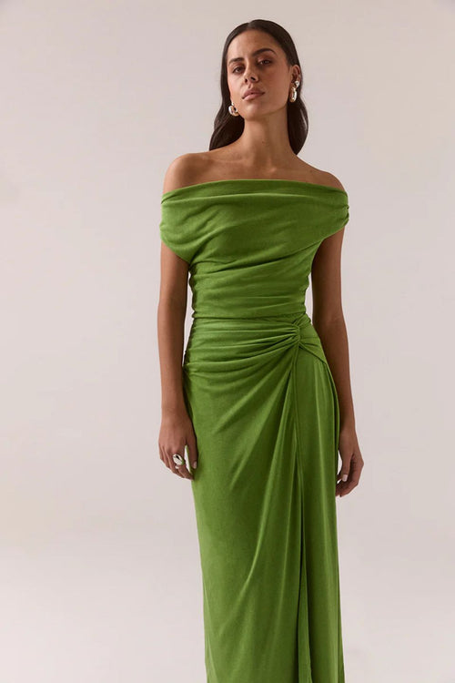 Woman wearing a green off-shoulder gown against a white background
