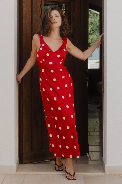 Woman in a red polka dot dress standing in a doorway.