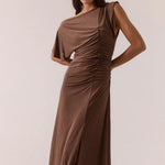 Woman wearing a brown ruched dress against a plain background