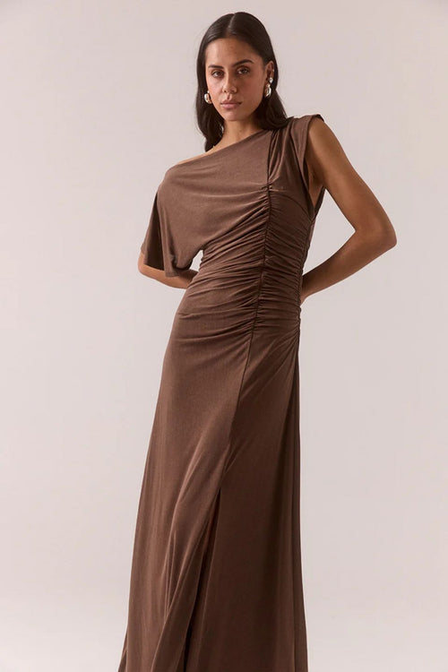 Woman wearing a brown ruched dress against a plain background