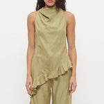 A model wearing a sage green two-piece set consisting of a sleeveless draped top with ruffles and matching wide-leg pants, paired with black sandals, against a plain white studio background.