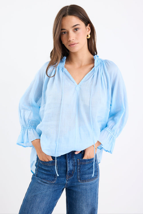 Woman wearing a light blue blouse and jeans on a white background