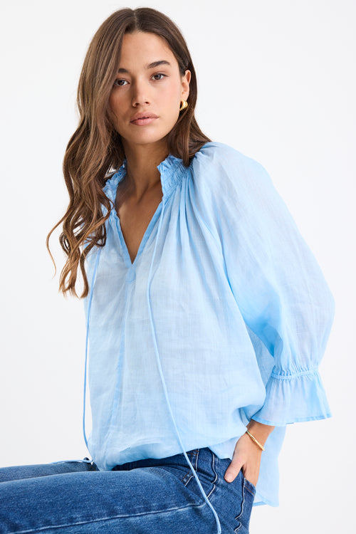 Woman wearing a light blue blouse with a white background