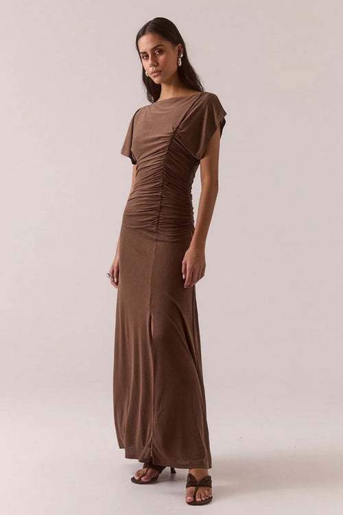 Woman wearing a brown ruched dress against a plain background