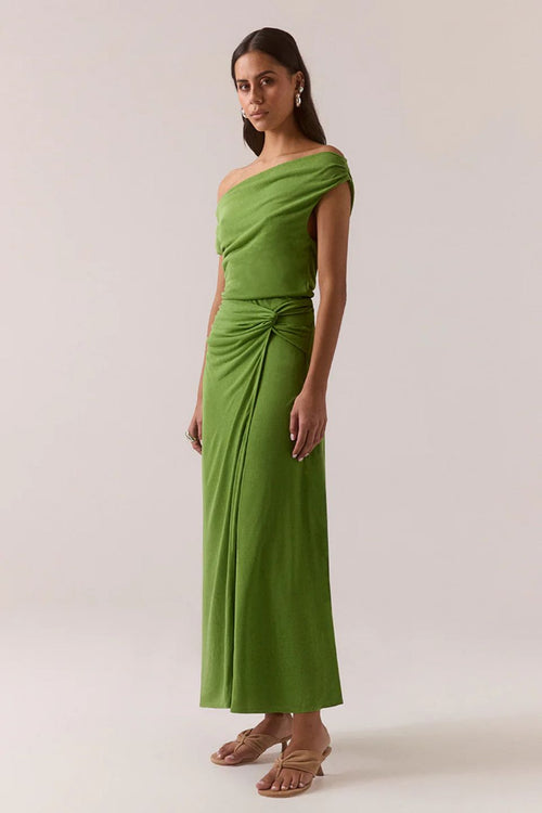 Woman wearing a green one-shoulder dress against a plain background