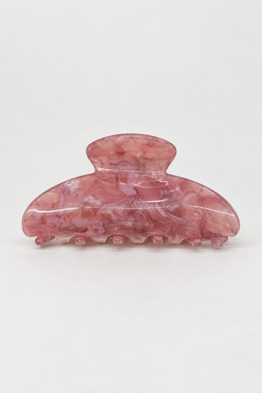 A translucent pink hair claw clip with a marbled pattern, photographed on a seamless light gray background.