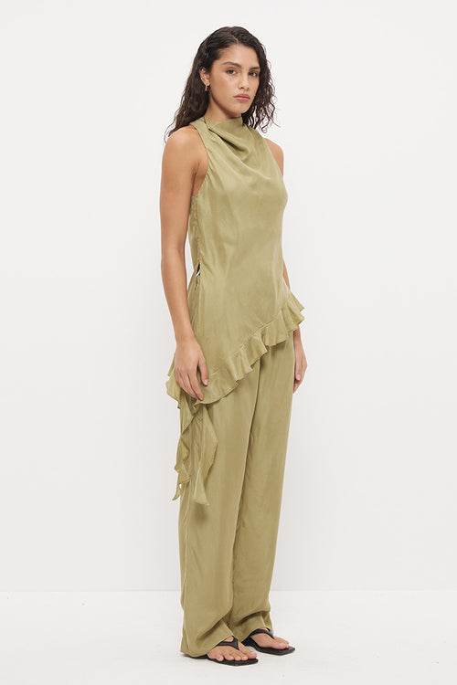 A woman modeling a sage green sleeveless ruffled top and matching wide-leg pants set, standing against a plain white studio background.