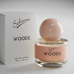 A round glass bottle of Sohum Woods eau de parfum with a glossy nude-toned spherical cap and a warm terracotta-pink label, featuring black and mustard-yellow text for an earthy, sophisticated aesthetic.