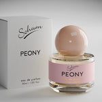 A round glass bottle of Sohum Peony eau de parfum with a blush-toned spherical cap and a soft pink label, featuring black and golden-yellow text for a fresh, feminine look.