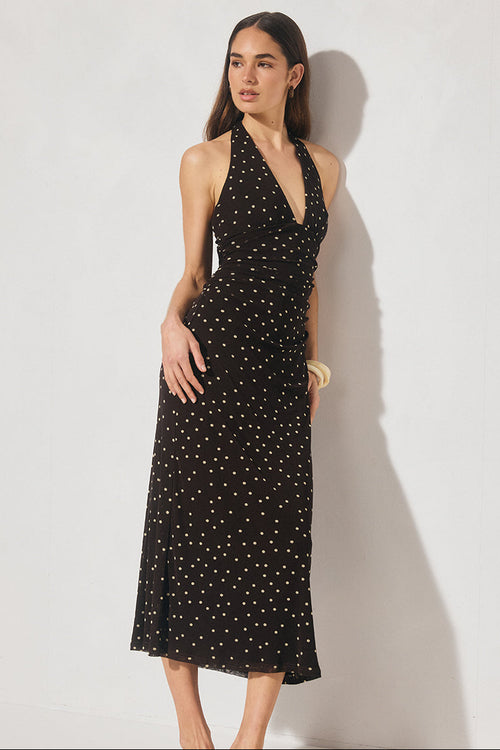 Woman wearing a black dress with white polka dots against a white background