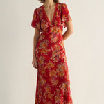 Woman wearing a red floral dress against a plain background