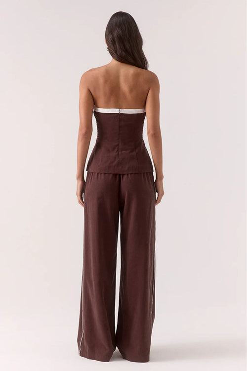 Woman wearing a strapless brown jumpsuit on a white background