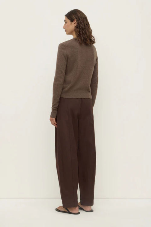 Woman wearing a brown sweater and pants on a white background